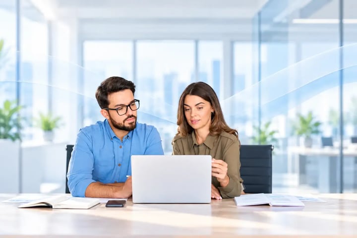 Dos profesionales trabajando juntos frente a una laptop